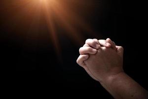 Hands folded in prayer on in church concept for faith, spirituality and religion, man praying in the morning. man hand with praying god. Person Christian men who have faith in Jesus worship in dark. photo