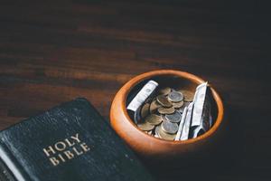 One tenth or tithe is basis on which Bible teaches us to give one tenth of first fruit to God. coins with Holy Bible. Biblical concept of Christian offering, generosity, and giving tithes in church. photo