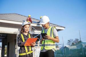 Construction inspector and female architect discuss with chief engineer Asia about installing solar panels on a construction project. Visit the construction site to install solar panels. photo