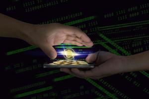 Human hand holding mobile smart phone with piles of golden coins and bitcoin symbol on binary background photo