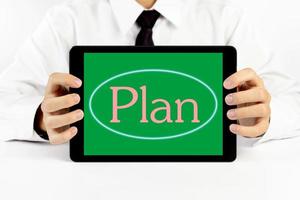Businessman holding a tablet with pink word Plan photo