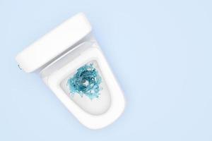 toilet bowl with vortex, twister water splash isolated on blue background. powerful suction for thorough cleaning concept, 3d render illustration, top view, clipping path photo