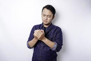 Calm spiritual handsome Asian guy praying with closed eyes. Serious peaceful young man with joining hands meditating. Belief concept photo