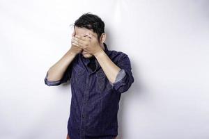 A portrait of an Asian man wearing a blue shirt isolated by white background looks depressed photo