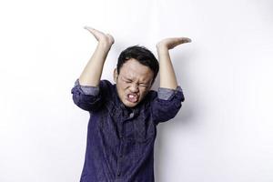 Shocked Asian man wearing blue shirt pointing at the copy space on top of him, isolated by white background photo