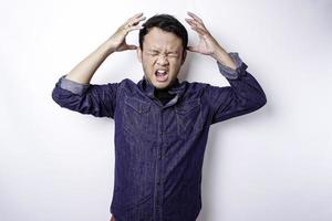 The angry and mad face of Asian man in blue shirt isolated white background. photo