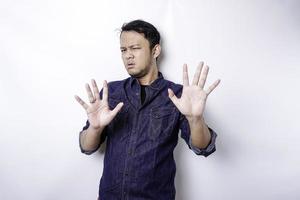hombre asiático guapo con camisa azul con gesto de mano pose de parada o prohibición con espacio de copia foto