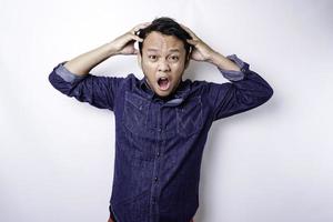 A portrait of an Asian man wearing a blue shirt isolated by white background looks depressed photo