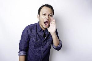 Young handsome man wearing a blue shirt shouting and screaming loud with a hand on his mouth. communication concept. photo