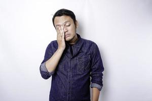 A portrait of an Asian man wearing a blue shirt isolated by white background looks depressed photo