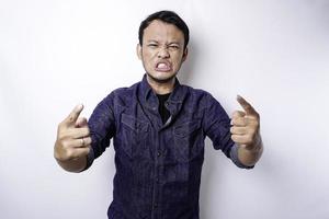 The angry and mad face of Asian man in blue shirt isolated white background. photo