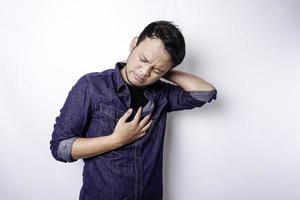 Tired upset young man wears blue shirt suffering from pain, muscle spasm at workplace. Fatigue, deadline, pain and incorrect posture photo