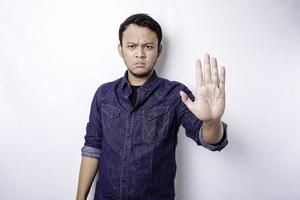 Handsome Asian man wearing blue shirt with hand gesture pose of stop or prohibition with copy space photo