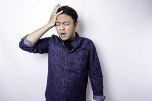 A portrait of an Asian man wearing a blue shirt isolated by white background looks depressed photo