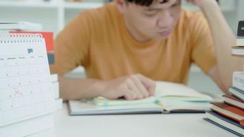 un étudiant asiatique a de l'anxiété à cause des examens, les hommes se préparent aux tests et apprennent les leçons à la bibliothèque. stress, désespoir, hâte, incompréhension lecture, découragement, attente, connaissance, fatigue video