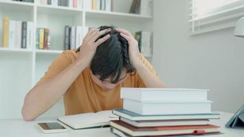 el estudiante asiático tiene ansiedad debido a los exámenes, los hombres se preparan para el examen y aprenden lecciones en la biblioteca. estrés, desesperación, prisa, malentendido lectura, desanimado, expectativa, conocimiento, cansado video