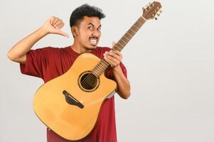 retrato de un joven asiático con una camiseta roja con una guitarra acústica aislada de fondo blanco foto