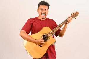 Portrait of Young Asian man in red t-shirt playing an acoustic guitar isolated on white background photo