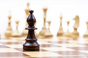 obispo contra figuras de ajedrez blancas en segundo plano. foto