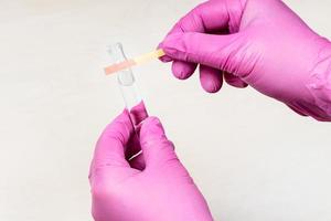 hands holding pink acid litmus test and test tube photo