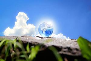 Globe on ground and grass with blue sky and cloud background. Ecology concept photo