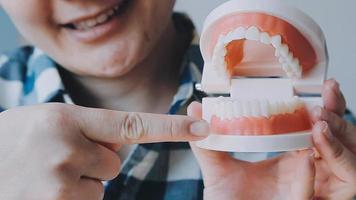 conceito de estomatologia, retrato parcial de menina com fortes dentes brancos, olhando para a câmera e sorrindo, dedos perto do rosto. closeup de jovem no dentista, estúdio, dentro de casa video