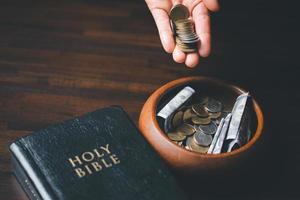 una décima o diezmo es la base sobre la cual la biblia nos enseña a dar una décima parte de las primicias a dios. monedas con la santa biblia. concepto bíblico de ofrenda cristiana, generosidad y entrega de diezmos en la iglesia. foto