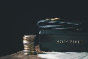 One tenth or tithe is basis on which Bible teaches us to give one tenth of first fruit to God. coins with Holy Bible. Biblical concept of Christian offering, generosity, and giving tithes in church. photo