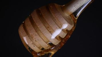 Flowing honey from a wooden honey spoon on a black background video