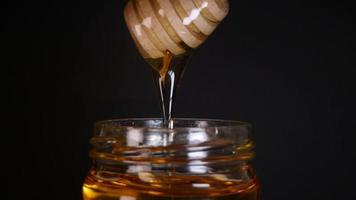 Flowing honey from a wooden honey spoon on a black background video