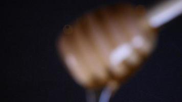 Flowing honey from a wooden honey spoon on a black background video