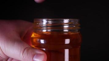 Flowing honey from a wooden honey spoon on a black background video