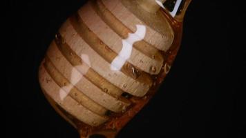 Flowing honey from a wooden honey spoon on a black background video