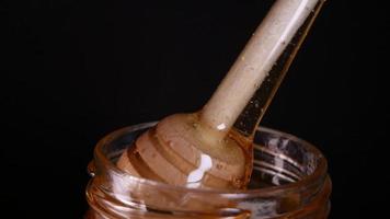 Flowing honey from a wooden honey spoon on a black background video