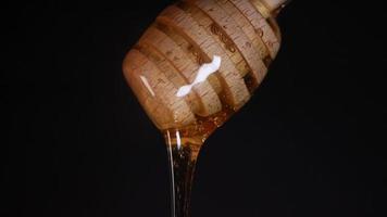 Flowing honey from a wooden honey spoon on a black background video