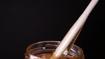 Flowing honey from a wooden honey spoon on a black background video