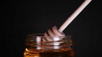 Flowing honey from a wooden honey spoon on a black background video