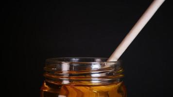 Flowing honey from a wooden honey spoon on a black background video