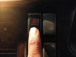 Finger press the emergency light button with the red triangle symbol. photo