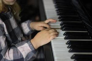 Little girl play piano,kids hands on piano keyboard close up,homeschooling,musical education.Growing talented child.Daily routine for toddler,side view of childs hands and piano photo