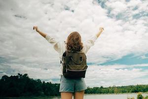 Young Asian girl tourist with hands raised up freedom fresh air travel. Woman traveler goes down to the river. Achieve your goals in your life path. The lifestyle of a tourist in an active. photo