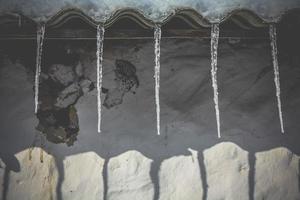 Close up icicles hanging from ruined house roof concept photo