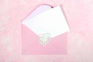 Pink envelope with lace heart and empty white blank sheet for text on pink. Top view. Close up. photo