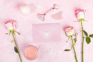 Natural pink quartz massager for face and scraper Guasha, envelope, roses, candle, hearts on pink. photo