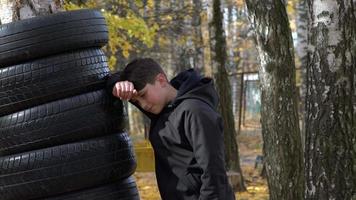 A boy boxing training on the park punching a punch bag hanging from a tree. video