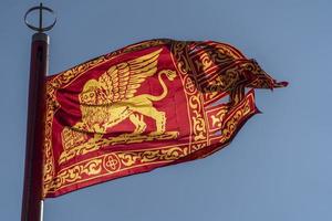 bandera roja de venecia con león dorado ondeando en el cielo foto