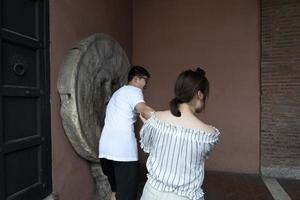 ROME, ITALY - JUNE 15 2019 - Tourist testing the mouth of truth mask photo