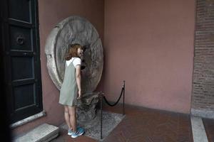 ROME, ITALY - JUNE 15 2019 - Tourist testing the mouth of truth mask photo