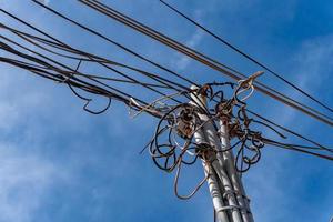 Electric cables tangle on wood post photo