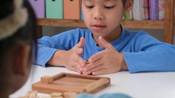 petits frères et sœurs jouant au jeu de société en bois tic-tac-toe sur la table dans le salon. la famille passe du temps ensemble le week-end. video